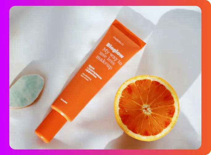Productfoto van een oranje tube naast een halve sinaasappel
